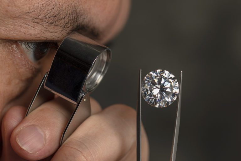 Closeup of a man evaluating a diamond under magnification. We buy diamonds.